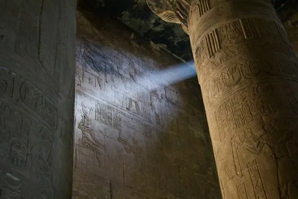 Sunlight shining between two columns on Egyptian hieroglyphs.