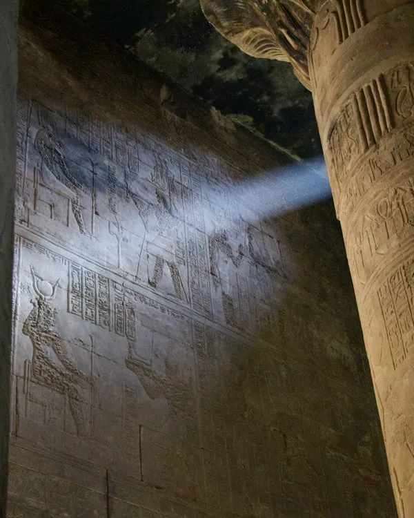 Sunlight shining between two columns on Egyptian hieroglyphs.