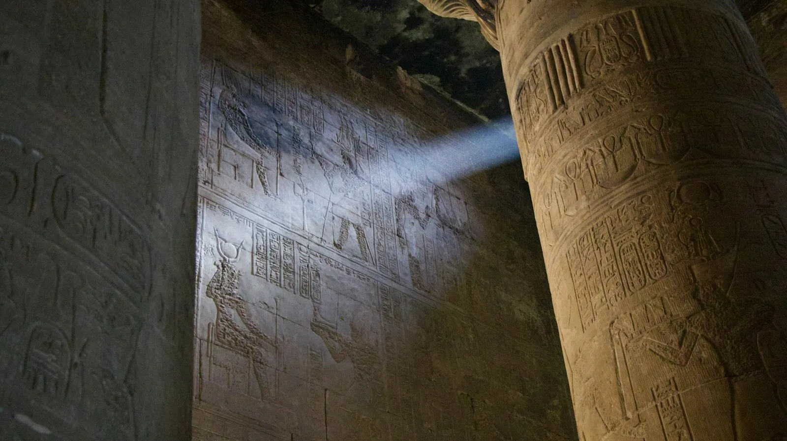 Sunlight shining between two columns on Egyptian hieroglyphs.